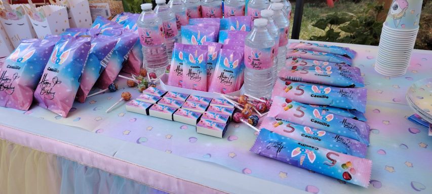 Table décorée avec des paquets de bonbons colorés et bouteilles d'eau.